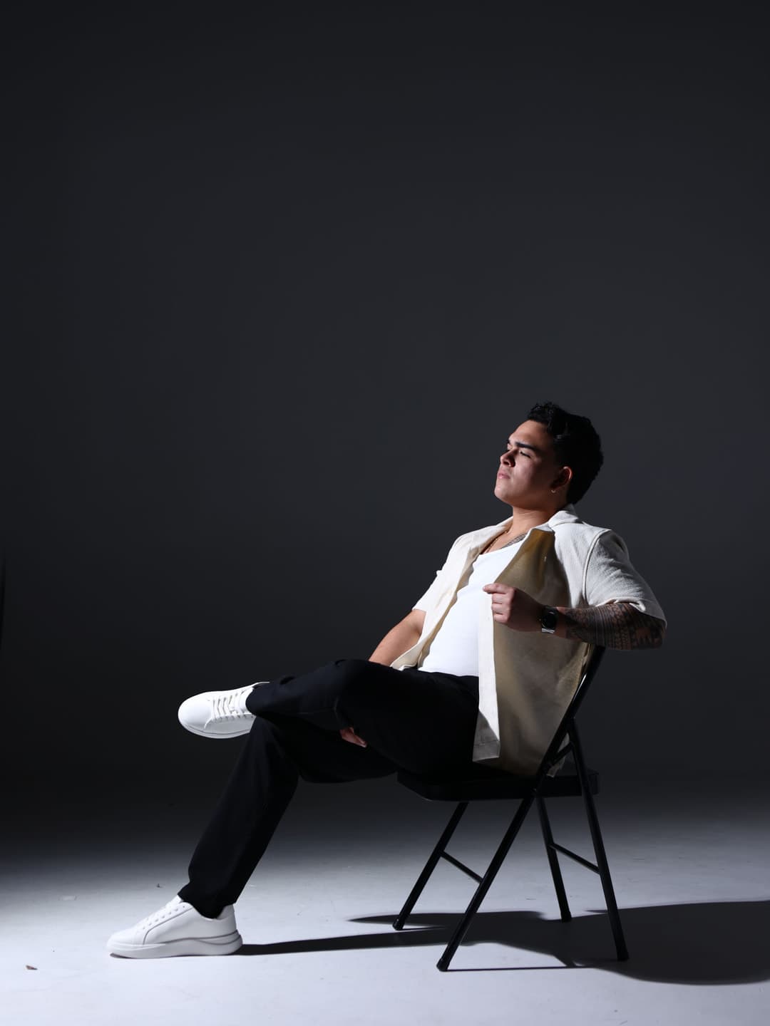 Sebastián seated in a studio, lit from the side against a dark backdrop